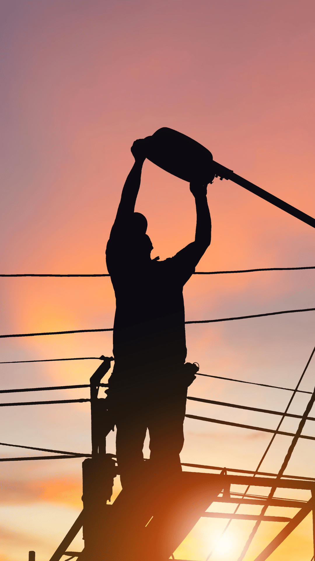 Utility worker with tablet at transmission pylon at dusk